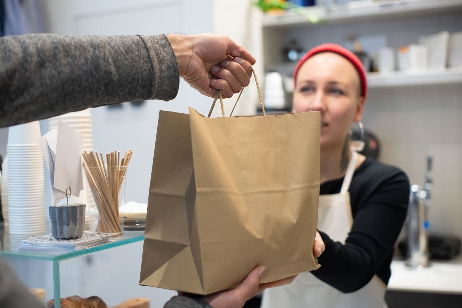 Remise d'un sac kraft de commande à emporter au comptoir